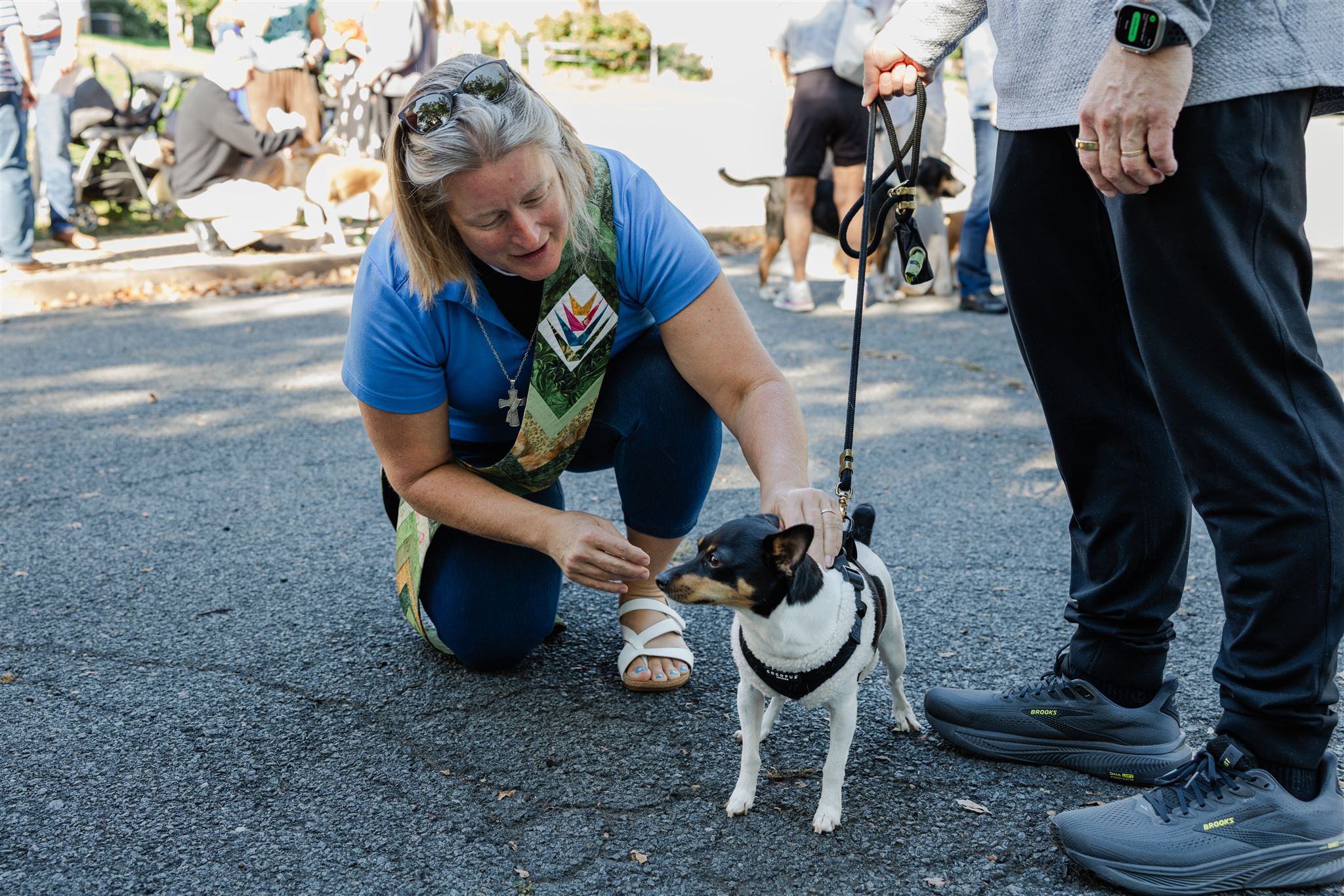The Ven. Holly Hanback greets a dog during an outdoor parish blessing.
